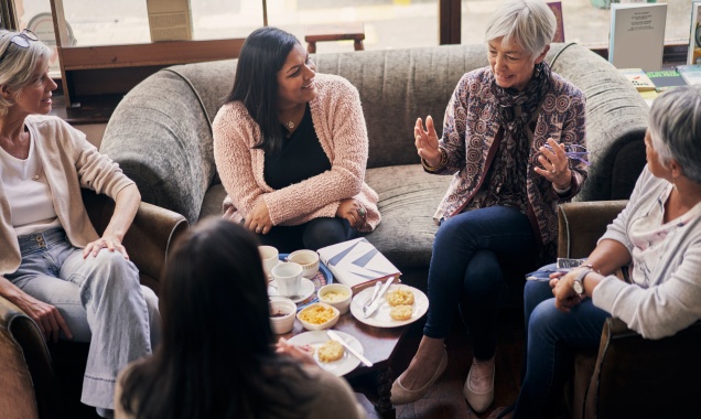 Group of five women sitting in a living room having a discussion