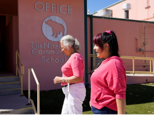 Two women in pink walk into a community school office in a Native American community. 