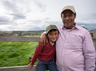 Father and young son standing in farm field