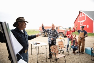 A group of adults on a farm voting by raising their hands