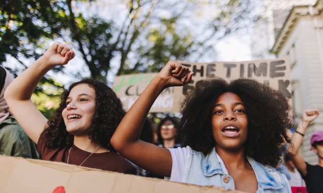 Two young people raising their fists and chanting at a protest