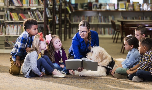 Adult woman reads to children in a library