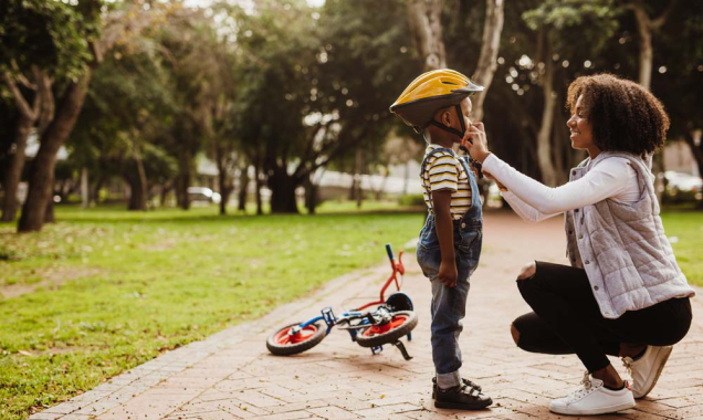 Adult woman fastens helmet on child