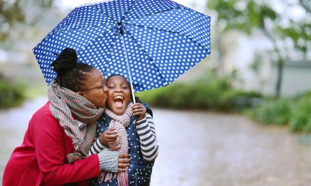 Black mother and daughter looking very happy while playing in the rain together. 
