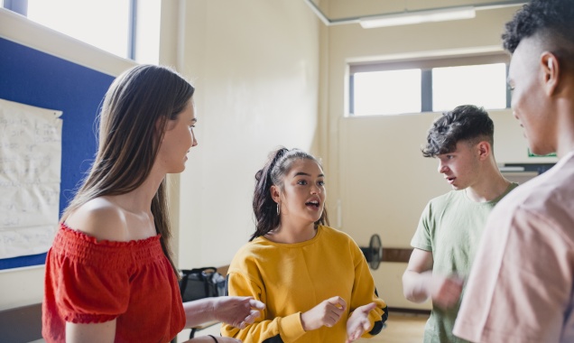 Four young people having a discussion inside a classroom