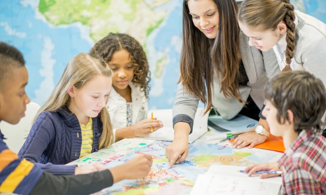 Elementary school children working together at a table with their teacher