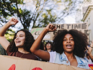 Two young people raising their fists and chanting at a protest