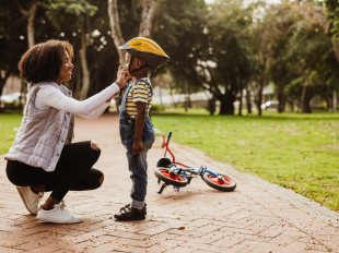 Woman fastens bike helmet on child