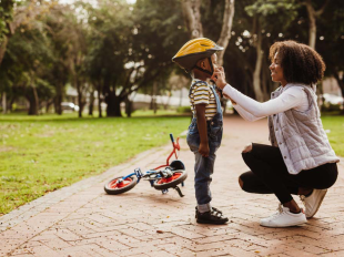 Adult woman fastens helmet on child