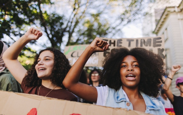 Two young people raising their fists and chanting at a protest