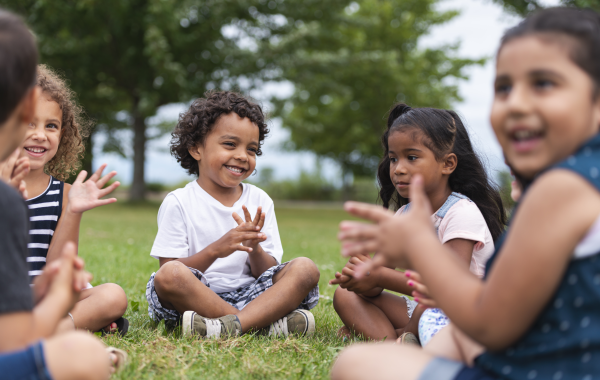 A group of children sit in a circle and clap hands