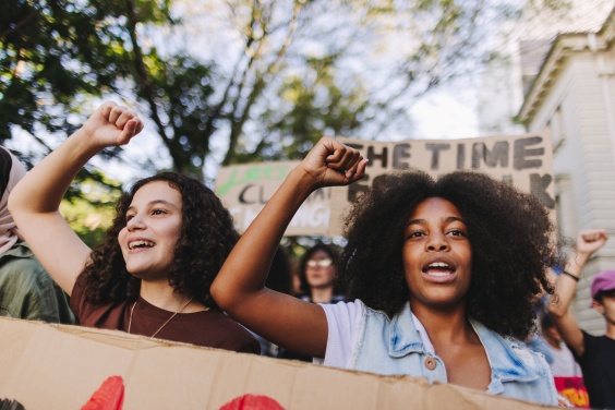 Two young people raising their fists and chanting at a protest