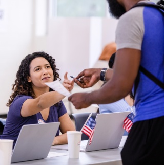 A young woman checks in a voter at a polling place