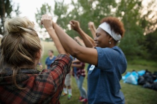 Two women in a larger circle of people hold raised hands to display solidarity.