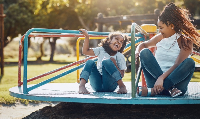 Young child and mother playing on a playground on a sunny day.