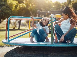 Young child and mother playing on a playground on a sunny day.